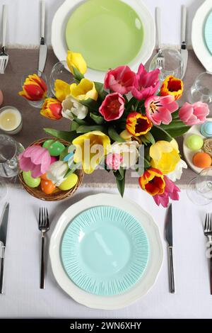Easter celebration. Festive table setting with beautiful flowers and painted eggs, flat lay Stock Photo