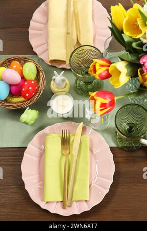 Easter celebration. Festive table setting with beautiful flowers and painted eggs, flat lay Stock Photo