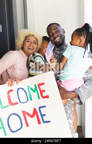 African American soldier in military uniform reunites with his family, holding his son and daughter Stock Photo