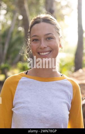 Young Caucasian woman smiles brightly in a natural outdoor setting on a hike Stock Photo