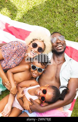 African American family enjoys a sunny day outdoors, lying on a striped blanket Stock Photo