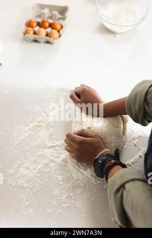 A young African American woman kneads dough on a floured surface with copy space Stock Photo