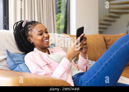 Young African American woman smiles while using her smartphone Stock Photo