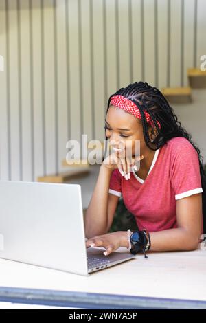 A young African American woman smiles while using a laptop with copy space Stock Photo