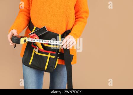 Female construction worker with measuring tape and tools on beige background, closeup Stock Photo