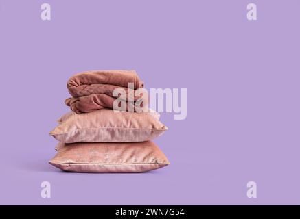 Stack of pillows with folded warm plaid on lilac background Stock Photo