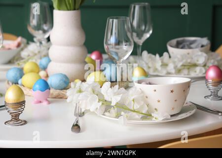 Festive Easter table setting, painted eggs, glasses and flowers Stock Photo