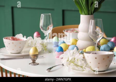 Festive Easter table setting, painted eggs, glasses and flowers Stock Photo
