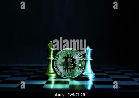 bit coin between golden king chess silver queen chess on board isolate black background Stock Photo