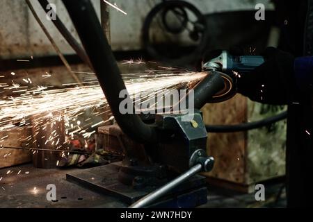 Closeup of unrecognizable man using angle grinder while doing metalwork, copy space Stock Photo