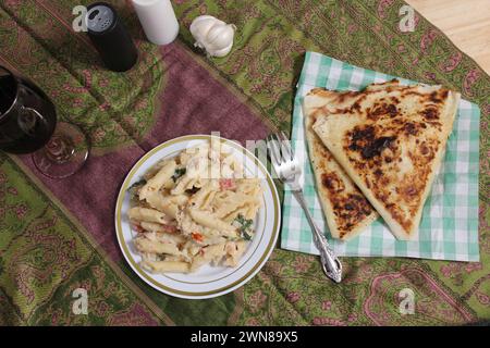 A bowl of pasta and pita bread on a table with checkered tablecloth Stock Photo