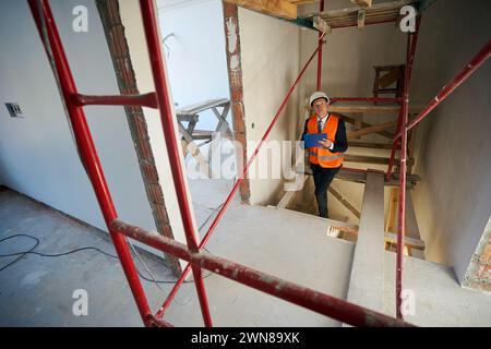 Construction foreman writing on clipboard while climbing stairs Stock Photo