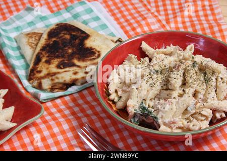 A bowl of pasta and pita bread on a table with checkered tablecloth Stock Photo