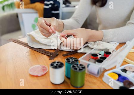 Recycle and Reuse. Designer sew from used denim fabric, old jeans. Upcycling process brings new life to old jeans Stock Photo