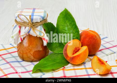 Jam of peaches on the table in a jar, next to a bowl of jam and spoons, peaches Stock Photo