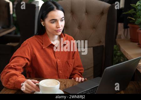 Beauty hispanic woman using laptop computer in cafe, drinking coffee, freelancer moods, laptop, hipster Stock Photo