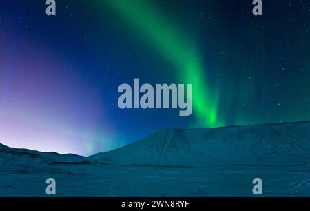 Aurora borealis over snowy mountains Stock Photo