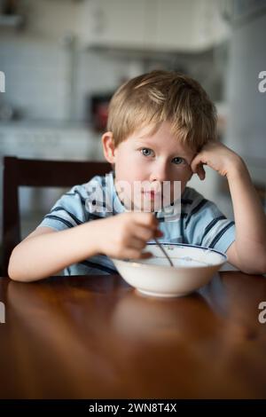 Young Boy eating Breakfast at Kitchen Table Stock Photo