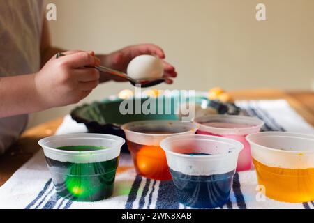 Child's hands coloring Easter eggs in plastic cups Stock Photo