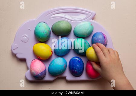 Child reaching for dyed Easter eggs on a plastic tray Stock Photo