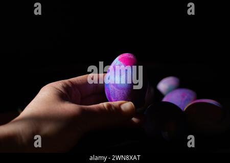 Hand holding a purple, blue and pink dyed Easter egg Stock Photo