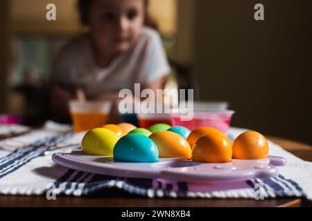 Child leaning over table with colored Easter eggs Stock Photo