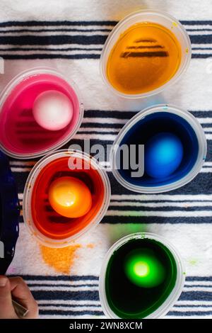 Eggs dyed in food coloring for Easter in plastic cups Stock Photo