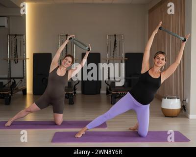 Two pregnant women doing yoga. Exercises with a gymnastic circle for Pilates.  Stock Photo