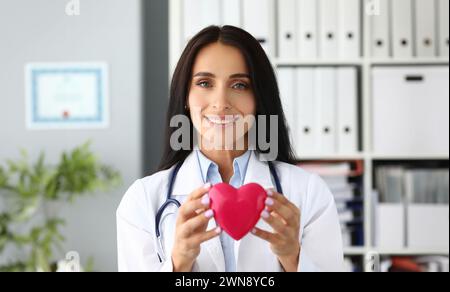 Beautiful smiling GP holding in hands red toy heart Stock Photo