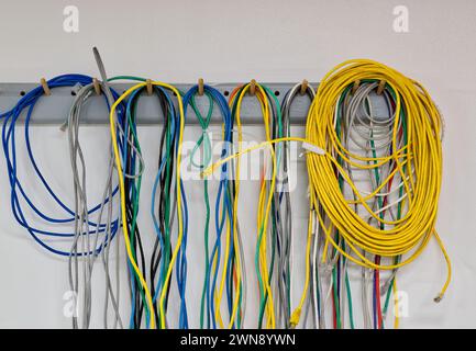 Colorful old electrical cables hanging on a wall. CAT5 Twisted pair cables for computer networks. Stock Photo