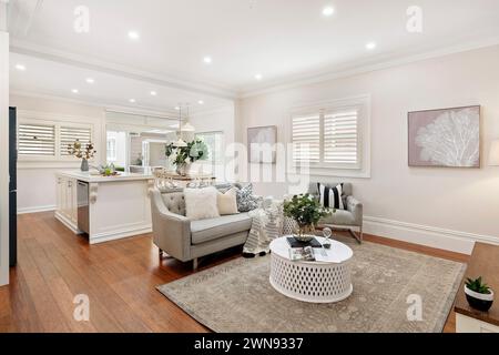 A bright white living room with hardwood floors and kitchen counter in modern home Stock Photo