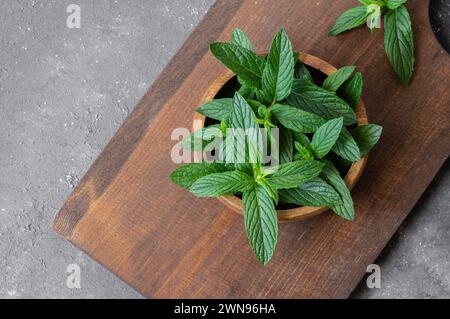 Fresh ripe green mint leaves in bowl on rustic background, green vegetable and spice Stock Photo