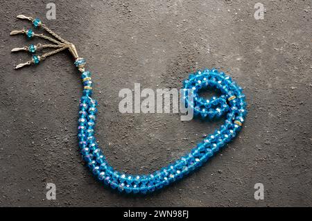 Arabic letter wav made with blue rosary on gray rustic background, islamic symbol Stock Photo