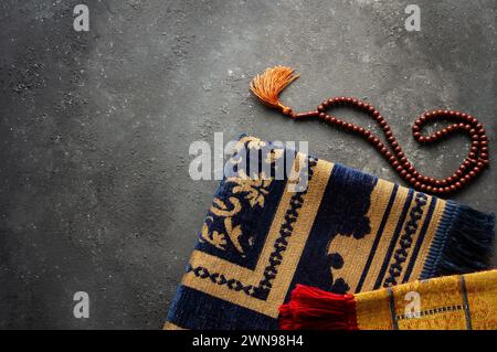 Prayer rug and rosary on stone background for worshiping in the month of Ramadan Stock Photo