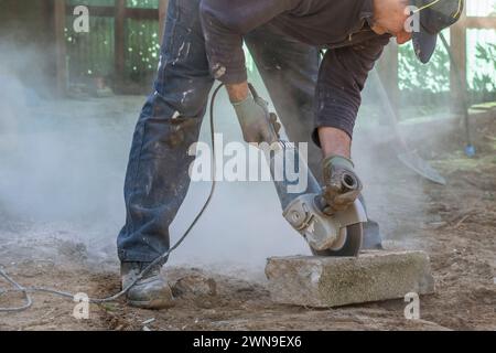 A worker cuts a concrete block with an electric angle grinder Stock Photo