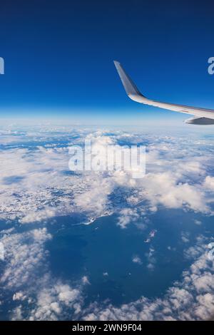 Airplane flying over color sky clouds during scenic sunset or sunrise cloudscape, view from plane window of wing turbines and horizon Stock Photo