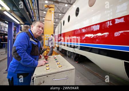 01 March 2024, Saxony-Anhalt, Halberstadt: The GDR prestige train SVT is slowly placed on the chassis using a lifting platform. After this step, the further refurbishment of the SVT can continue. Under the watchful eyes of numerous guests, the VT 18.16.10 engine car was raised to approx. 2.60 meters in the VIS Halberstadt railroad depot using four lifting jacks, then the bogies were positioned exactly under the vehicle. Finally, the vehicle is slowly lowered until it stands on its own wheels again. The train should be ready for operation again in the 3rd quarter of 2024. The first test runs wi Stock Photo