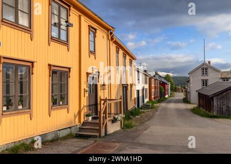 Charming yellow and red Scandinavian homes stand in a row in historic Roros, their quaint windows reflecting the calm of a late Nordic summer day Stock Photo