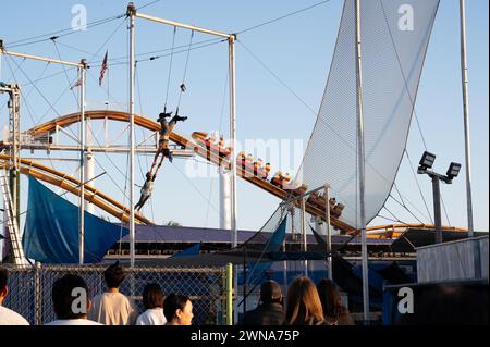 SANTA MONICA, CALIFORNIA, USA: The roller coaster and trapeze with acrobats on the world famous Santa Monica Pier in Santa Monica, California. Stock Photo