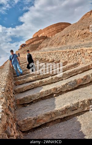 Tourists walk down a stone stair after visiting the Tower of Silence (Dakhmeh), a structure used in Zoroastrian burial tradition. Yazd, Iran.  Zoroast Stock Photo