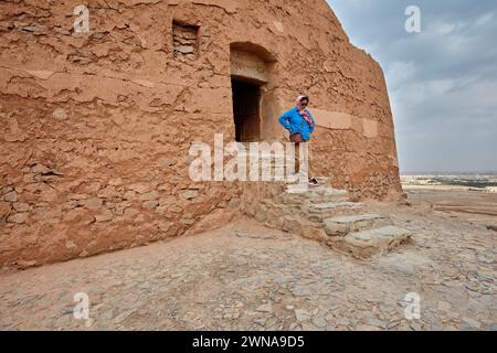 A woman walks down a stone stair after visiting the Tower of Silence (Dakhmeh), a structure used in Zoroastrian burial tradition. Yazd, Iran. Stock Photo