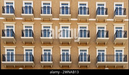 Front view of a modern residential brown brick building with balconies and Windows, close-up, pattern Stock Photo