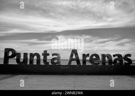 Evening light on the metal Punta Arenas sign near the shore. The sign commemorates 500 years since the discovery of the Strait of Magellan. Stock Photo