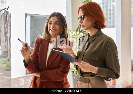 Two happy business women discussing sticky notes working together in office. Stock Photo