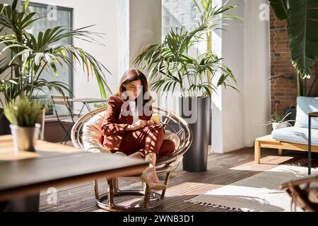 Busy middle aged business woman using phone sitting in chair in office. Stock Photo