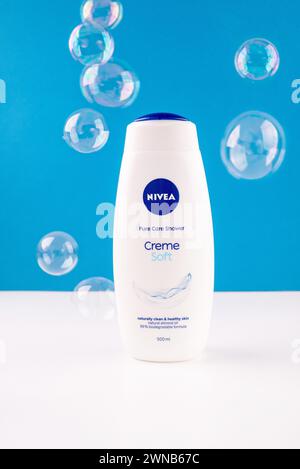 Ukraine, Kyiv. 19.02.2024. - Bottle of shower gel Nivea with soap bubbles on blue background. Nivea products for bathroom. Stock Photo