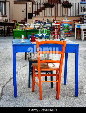 a table with colored chairs from a restaurant in Marzamemi, a picturesque Sicilian sailors' village Stock Photo