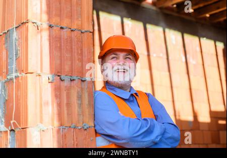 House construction. Portrait of builder, engineer, architect in hard hat on construction site. Handsome bearded inspector, foreman, craftsman in Stock Photo