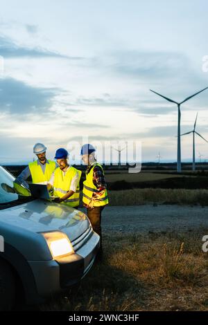 Engineers teamwork discussing renewable energy project at wind turbine farm Stock Photo