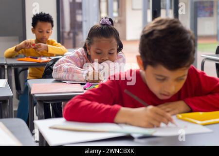 Biracial girl and boys are focused on their schoolwork in a school classroom Stock Photo